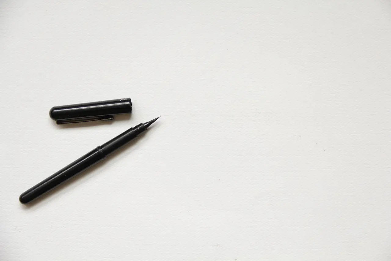 A pen resting on a blank sheet of paper on a desk