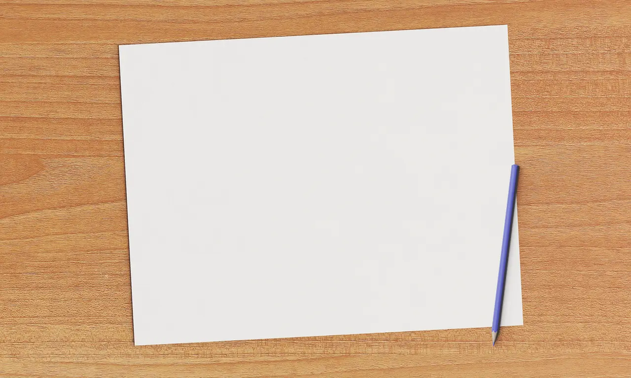 A blank sheet of paper and a pencil on a wooden desk